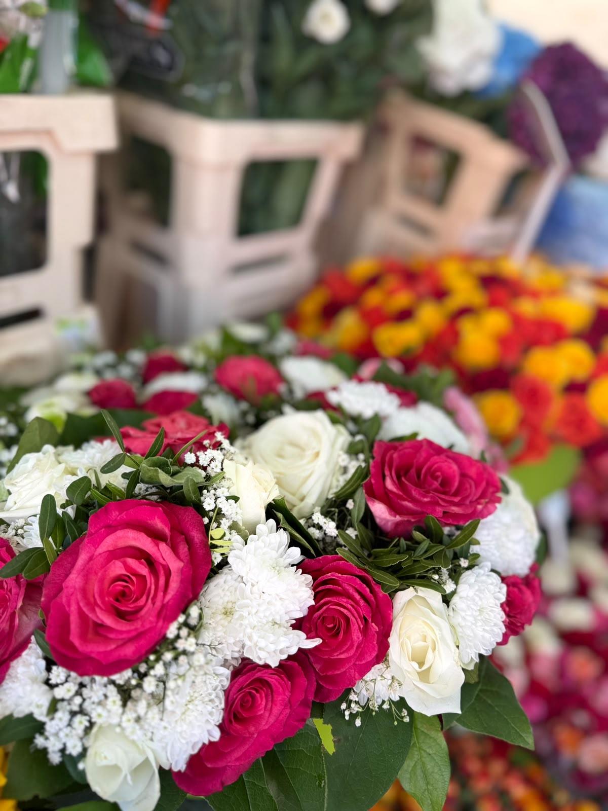 Rosa Rosen und weiße Blüten in einem frisch gebundenen Strauß am Marktstand